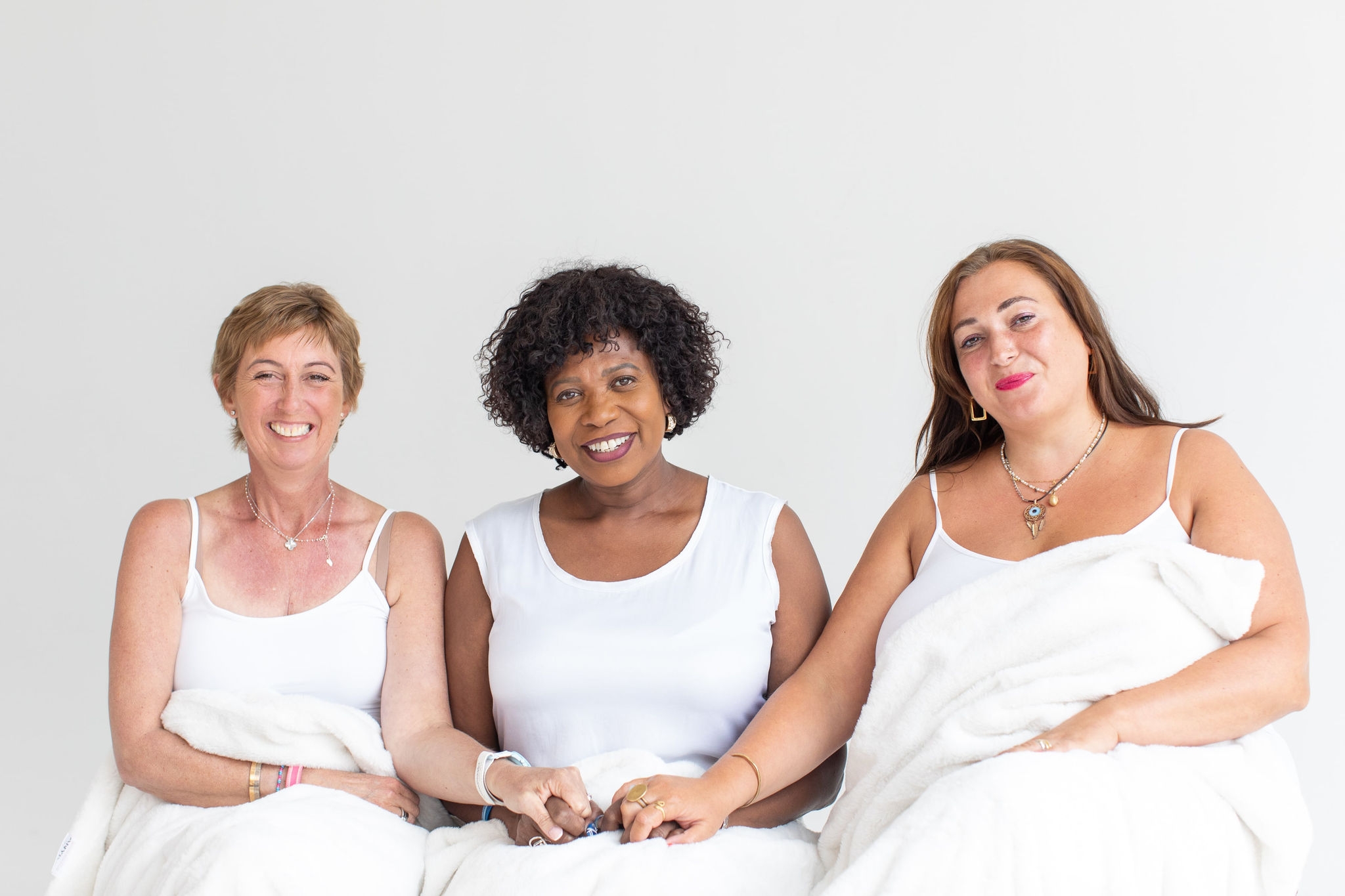 three woman sitting together holding hands