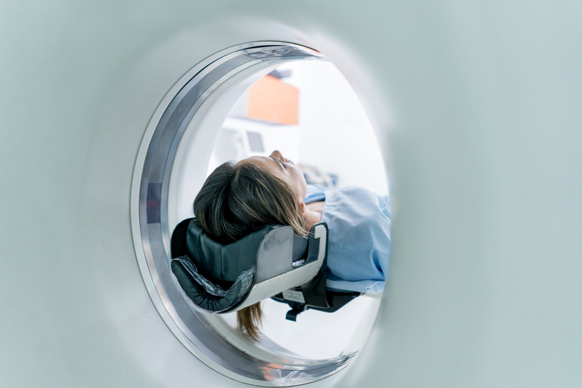 Patient lying down getting a CT scan at the hospital - healthcare and medicine concepts