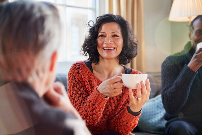 Plano frontal de mujer sonriendo y tomando café 